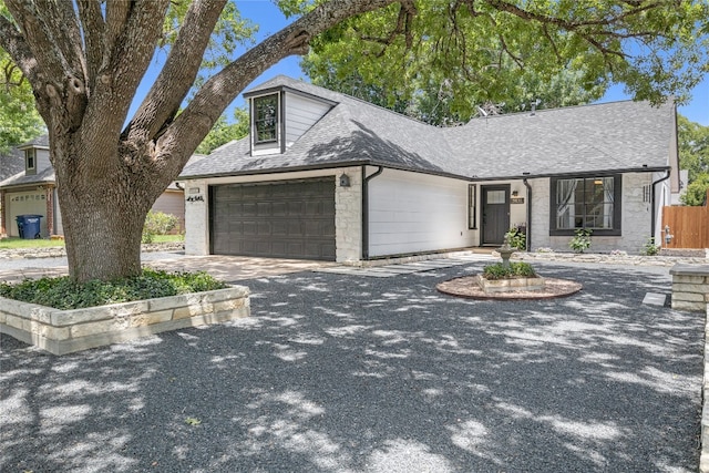 9831 Briar Ridge Dr, Austin, TX 78748 - view of front facade featuring a shingled roof, a garage, stone siding, and driveway