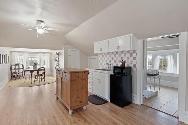 517 N 9th St, Temple, TX 76501 - kitchen featuring black microwave, light wood-style floors, a ceiling fan, lofted ceiling, and white cabinetry