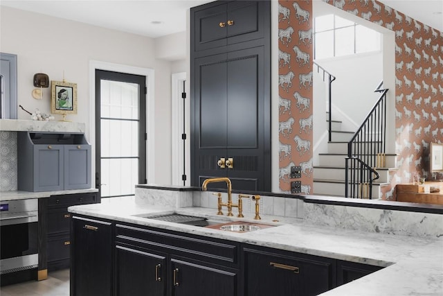 901 Wayside Dr, Austin, TX 78703 - kitchen with a sink, dark cabinets, wallpapered walls, and light stone countertops