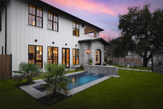 901 Wayside Dr, Austin, TX 78703 - back of house at dusk featuring board and batten siding, a balcony, french doors, and a patio area