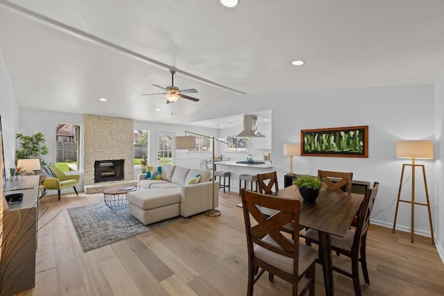 11305 Songbird Cv, Austin, TX 78750 - dining room featuring vaulted ceiling, light wood-style flooring, a fireplace, and a ceiling fan
