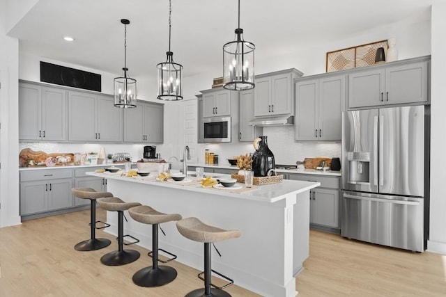100 Silent Grove Ct, Georgetown, TX 78642 - kitchen with stainless steel appliances, gray cabinets, under cabinet range hood, light wood-style floors, and recessed lighting