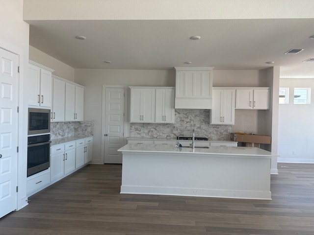 100 Silent Grove Ct, Georgetown, TX 78642 - kitchen featuring stainless steel appliances, decorative backsplash, white cabinets, a center island with sink, and dark wood finished floors