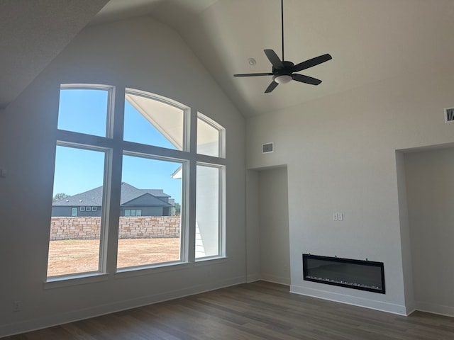 100 Silent Grove Ct, Georgetown, TX 78642 - unfurnished living room with healthy amount of natural light, high vaulted ceiling, dark wood-type flooring, a glass covered fireplace, and a ceiling fan
