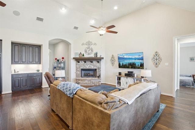 living area featuring a ceiling fan, arched walkways, visible vents, and dark wood-type flooring