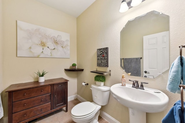 bathroom with tile patterned floors, toilet, baseboards, and a sink