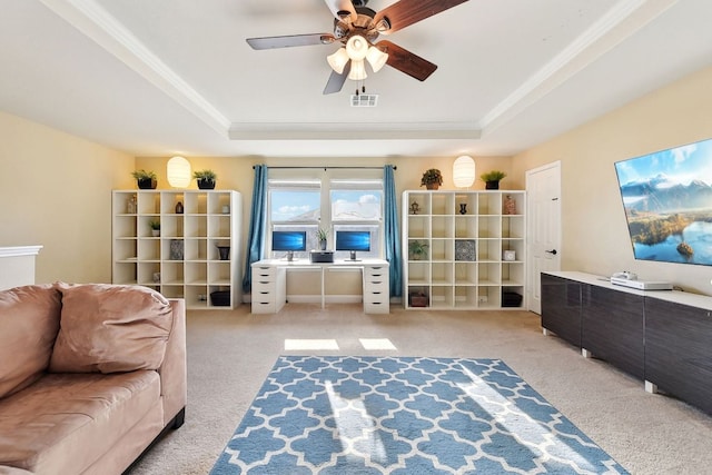 sitting room with a tray ceiling, visible vents, ornamental molding, carpet flooring, and ceiling fan