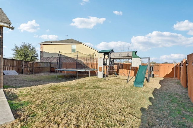view of yard featuring a trampoline, a fenced backyard, and a playground