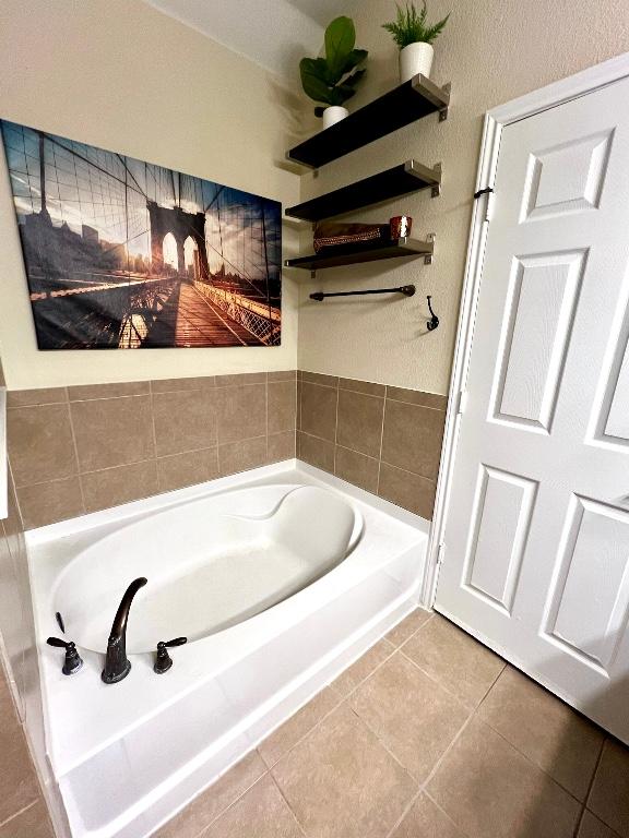bathroom with tile patterned floors and a bath