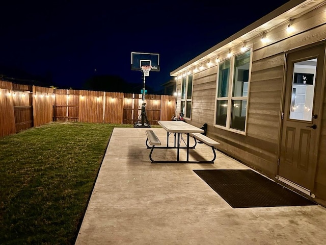 patio at twilight with a fenced backyard and a lawn