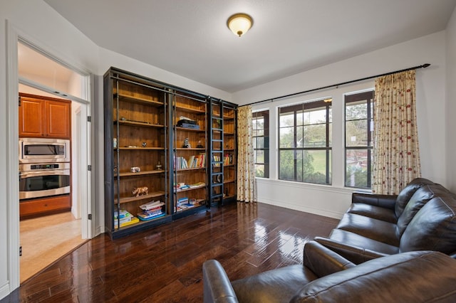 sitting room with baseboards and dark wood-style flooring