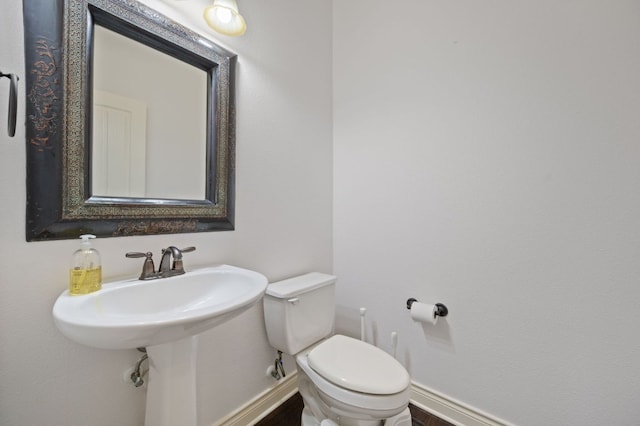 half bath with baseboards and toilet