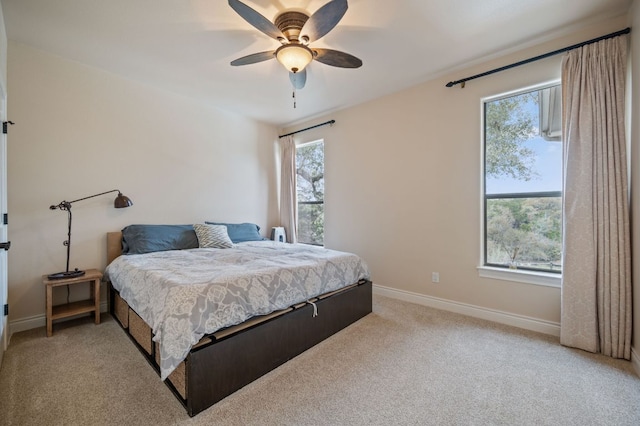 bedroom with light carpet, baseboards, and a ceiling fan