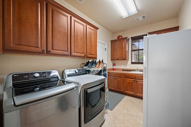 washroom with light tile patterned flooring, visible vents, washer and dryer, and cabinet space