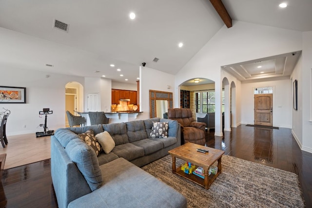 living area with arched walkways, dark wood-type flooring, beamed ceiling, and visible vents