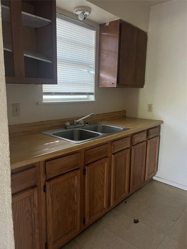 410 Railroad St, San Marcos, TX 78666 - kitchen featuring a sink, open shelves, brown cabinets, and baseboards