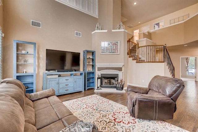19803 Mallard Pond Trl, Pflugerville, TX 78660 - living area featuring a towering ceiling, stairway, wood finished floors, and a fireplace with raised hearth