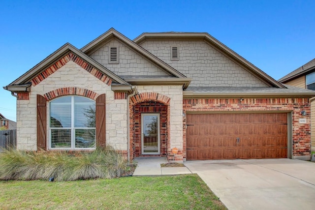 view of front of home featuring a garage, a front yard, stone siding, and concrete driveway