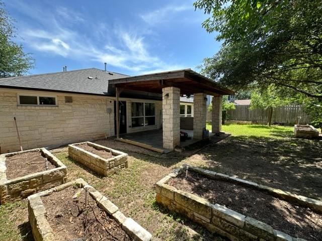 11708 Bittern Holw, Austin, TX 78758 - back of property featuring a garden, a patio, stone siding, and a shingled roof