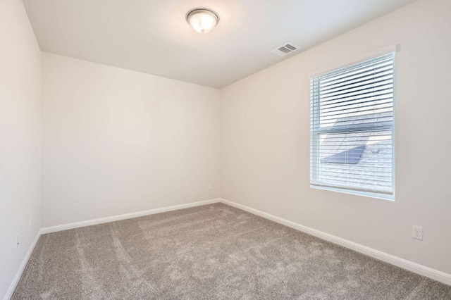spare room with carpet, baseboards, and visible vents