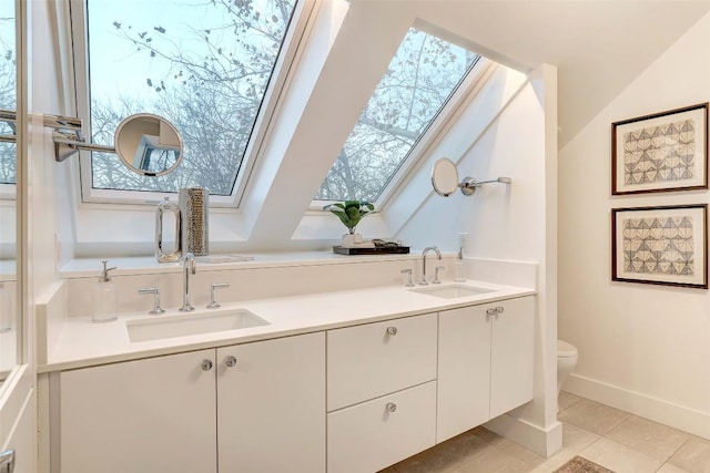 2009 Riverview St, Austin, TX 78702 - bathroom featuring a skylight, toilet, double vanity, tile patterned flooring, and baseboards