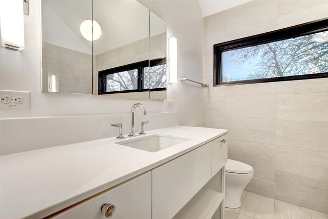 2009 Riverview St, Austin, TX 78702 - bathroom featuring vanity, toilet, tile patterned floors, and tile walls