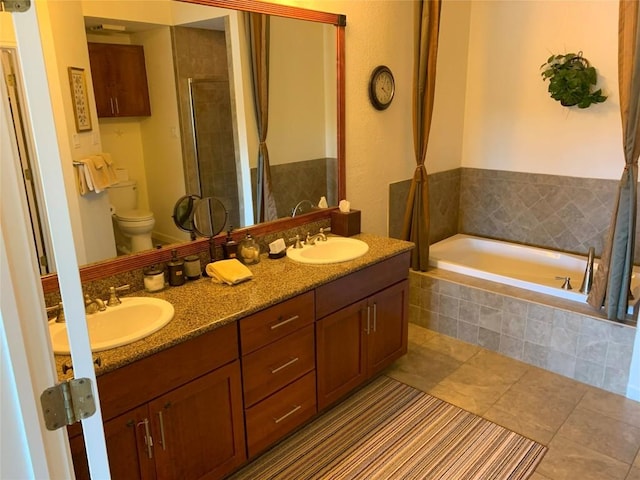 full bathroom featuring toilet, a sink, a garden tub, and a shower stall