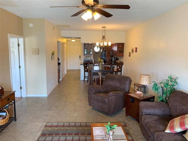 living room featuring light tile patterned floors, ceiling fan with notable chandelier, and baseboards