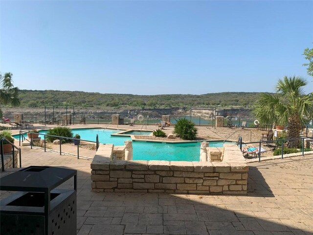 pool featuring fence, a forest view, and a patio area