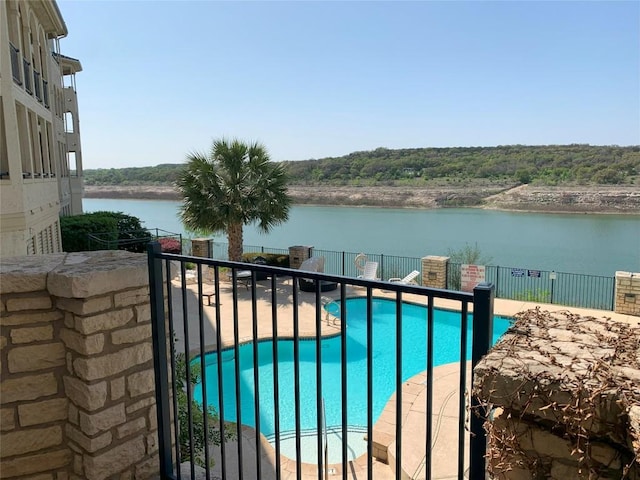 community pool featuring a water view, fence, and a patio area