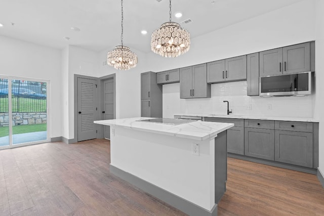 2450 Wickersham Ln Unit 2013, Austin, TX 78741 - kitchen with stainless steel microwave, a chandelier, a sink, wood finished floors, and recessed lighting