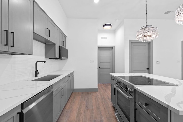 2450 Wickersham Ln Unit 2013, Austin, TX 78741 - kitchen featuring stainless steel appliances, a sink, dark wood-type flooring, decorative backsplash, and hanging light fixtures