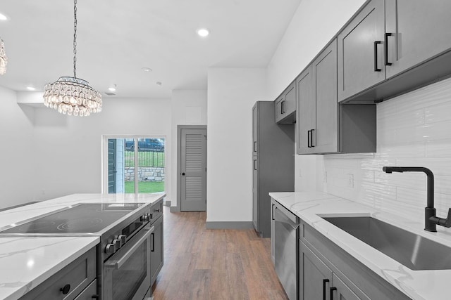 2450 Wickersham Ln Unit 2013, Austin, TX 78741 - kitchen with appliances with stainless steel finishes, a sink, wood finished floors, gray cabinetry, and backsplash