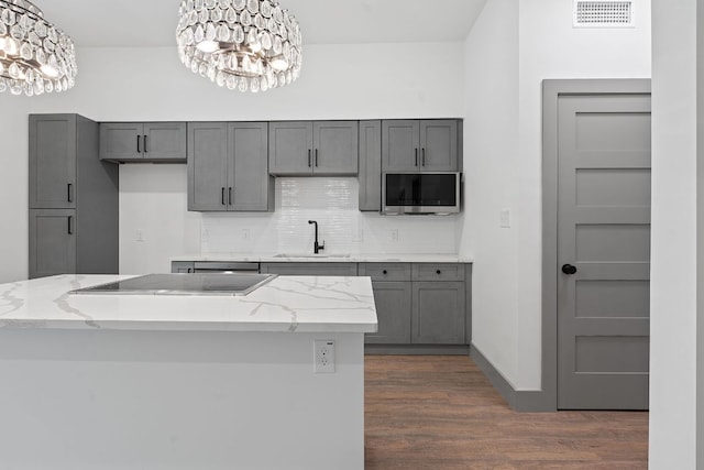 2450 Wickersham Ln Unit 2013, Austin, TX 78741 - kitchen with a sink, stovetop, stainless steel microwave, a chandelier, and dark wood-style flooring