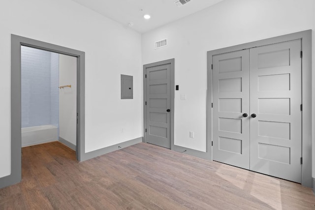 2450 Wickersham Ln Unit 2013, Austin, TX 78741 - unfurnished bedroom featuring electric panel, wood finished floors, a closet, and recessed lighting