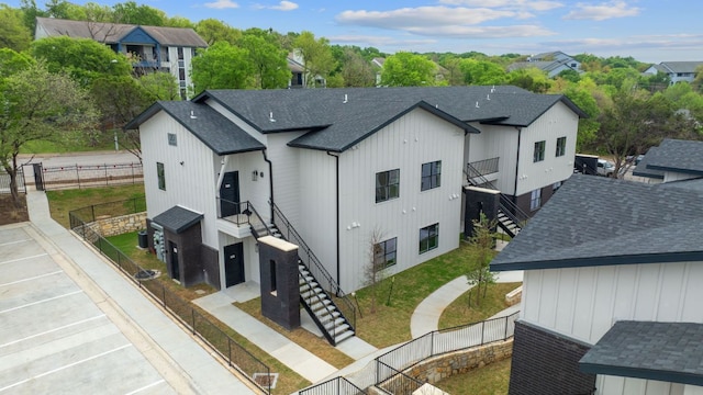 2450 Wickersham Ln Unit 2013, Austin, TX 78741 - view of side of home with stairway, a fenced backyard, and a shingled roof