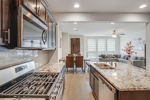 13800 Lyndhurst St Unit 325, Austin, TX 78717 - kitchen with appliances with stainless steel finishes, a sink, light stone counters, a kitchen island with sink, and recessed lighting