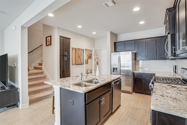 13800 Lyndhurst St Unit 325, Austin, TX 78717 - kitchen featuring appliances with stainless steel finishes, light stone countertops, a sink, an island with sink, and tasteful backsplash