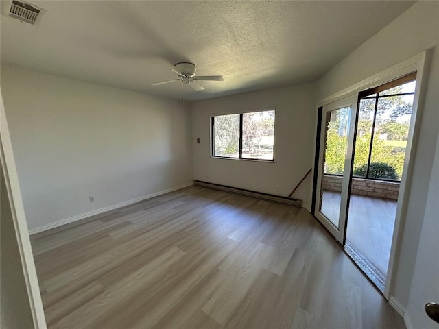 712 Rolling Green Dr, Lakeway, TX 78734 - unfurnished room with a textured ceiling, visible vents, ceiling fan, a baseboard heating unit, and light wood-type flooring
