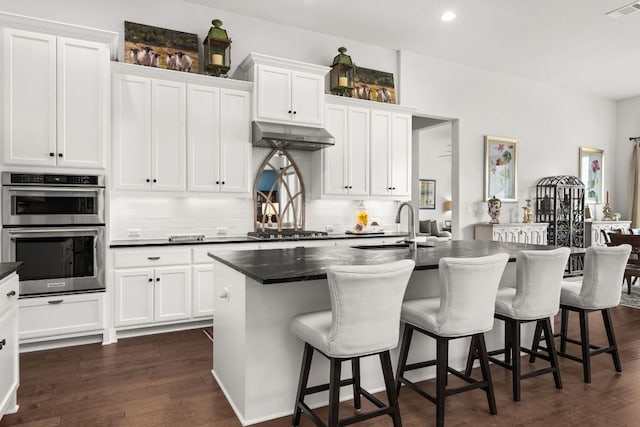 kitchen with tasteful backsplash, a sink, dark countertops, stainless steel appliances, and visible vents