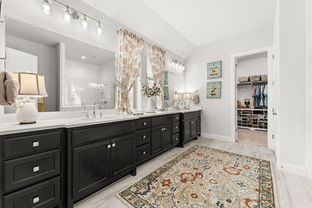 bathroom with a sink, a shower stall, marble finish floor, a walk in closet, and double vanity
