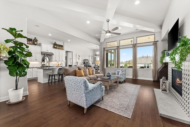 living area featuring a fireplace with flush hearth, ceiling fan, dark wood-style floors, beam ceiling, and recessed lighting