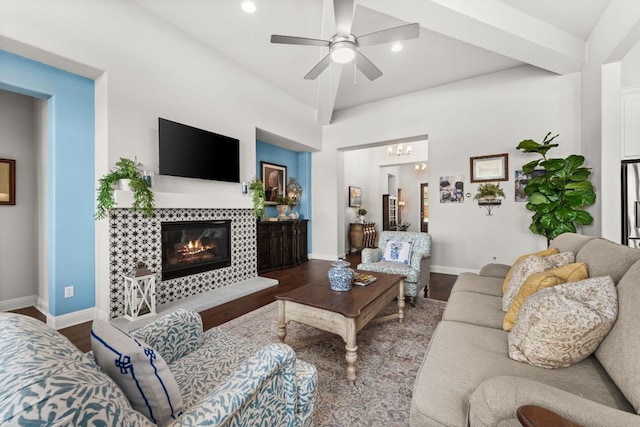 living room with wood finished floors, a tiled fireplace, baseboards, and ceiling fan with notable chandelier