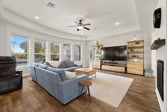 1924 Portobello Rd, Leander, TX 78641 - living room with a ceiling fan, wood finished floors, a fireplace, a raised ceiling, and recessed lighting