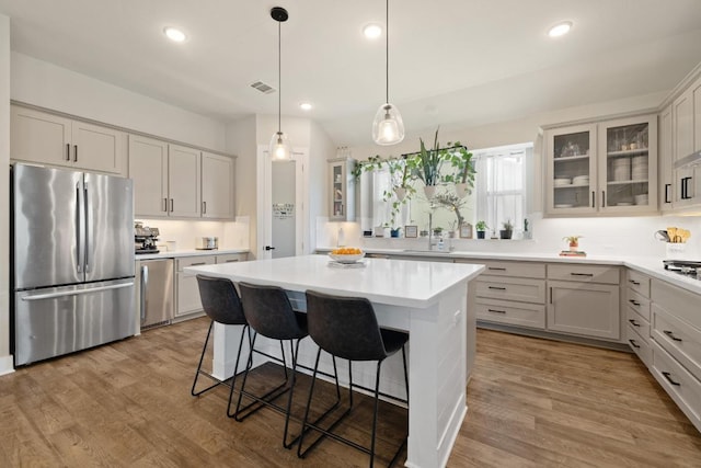 1924 Portobello Rd, Leander, TX 78641 - kitchen featuring appliances with stainless steel finishes, a breakfast bar, a kitchen island, wood finished floors, and recessed lighting