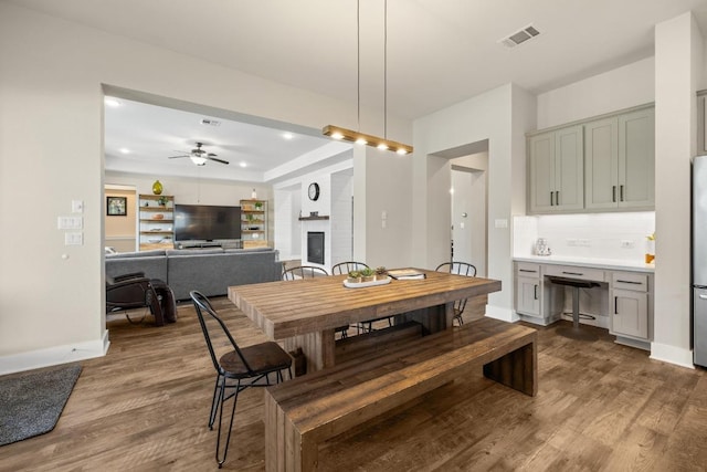 1924 Portobello Rd, Leander, TX 78641 - dining space featuring dark wood-style flooring, a glass covered fireplace, a ceiling fan, and recessed lighting