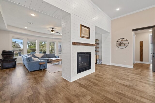 1924 Portobello Rd, Leander, TX 78641 - living area featuring wood finished floors, ceiling fan, a glass covered fireplace, ornamental molding, and recessed lighting