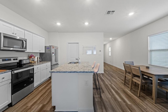412 Gemsbok Rd, Hutto, TX 78634 - kitchen with stainless steel appliances, dark wood-style flooring, a center island with sink, white cabinetry, and recessed lighting