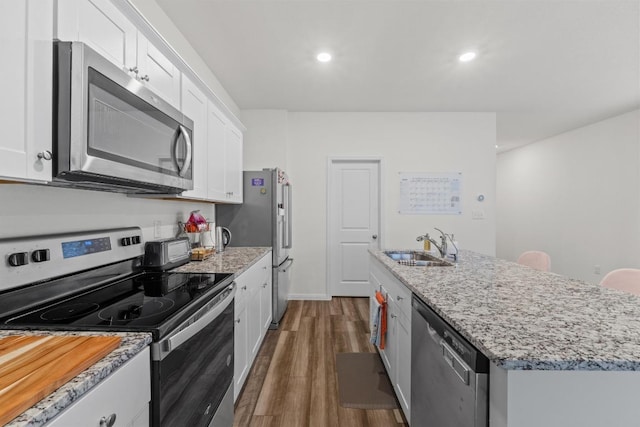 412 Gemsbok Rd, Hutto, TX 78634 - kitchen featuring appliances with stainless steel finishes, white cabinetry, dark wood finished floors, a kitchen island with sink, and light stone counters