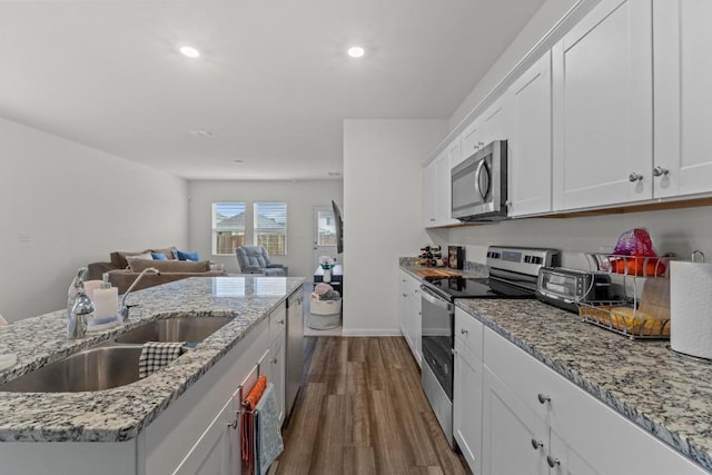 412 Gemsbok Rd, Hutto, TX 78634 - kitchen featuring appliances with stainless steel finishes, dark wood finished floors, open floor plan, white cabinetry, and recessed lighting